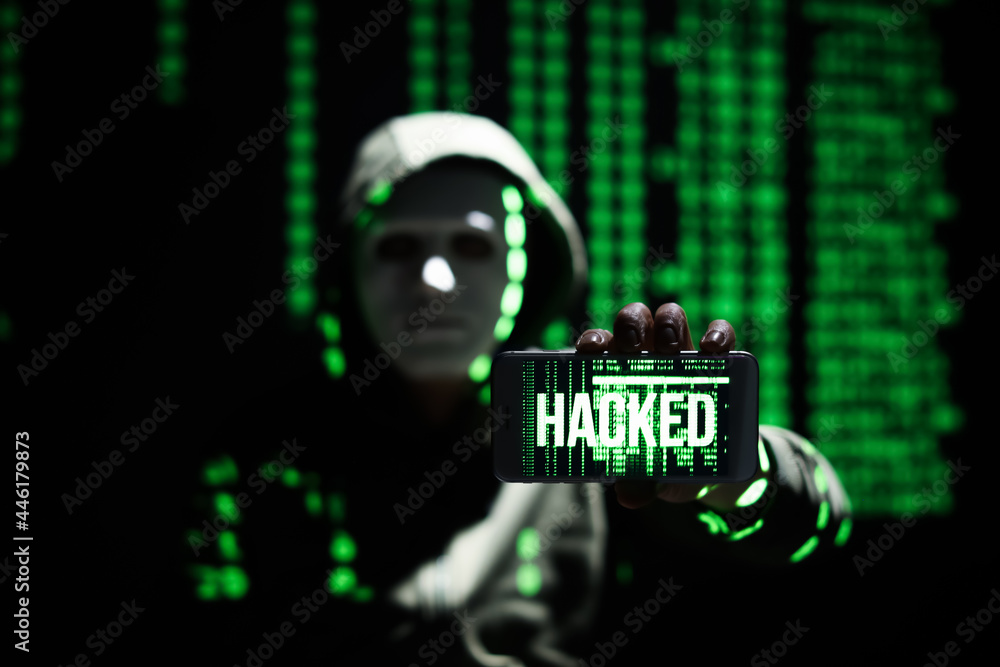 Poster hacker holding mobile phone with word hacked on screen against dark background