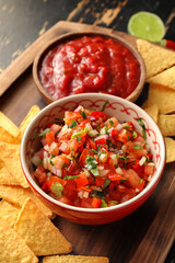 Bowl of tasty salsa sauce and nachos on table