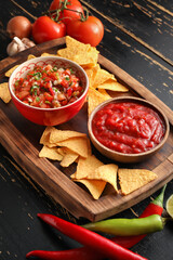 Bowls of tasty salsa sauces and nachos on table