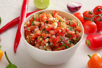Bowl of tasty salsa sauce on white background