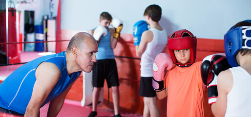 Group of children practicing with trainer on boxing ring at gym