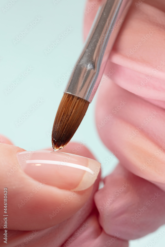 Wall mural close up process of applying red varnish. woman in salon receiving manicure by nail beautician. red 