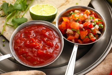 Bowls of tasty salsa sauces on tray