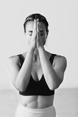 A woman with braids in her hair is doing Namaste pose.