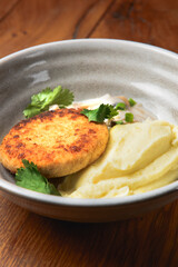 Meat cutlet, mashed potatoes and mushroom gravy in a bowl over rustic wooden background. Healthy dinner