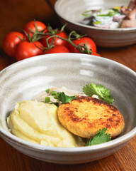 Meat cutlet, mashed potatoes and mushroom gravy in a bowl over rustic wooden background. Healthy dinner