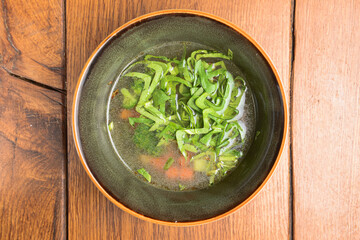 Soup Kharcho, traditional Georgian soup, checken broth in a bowl over rustic wooden background.