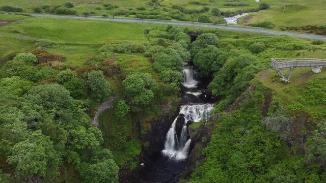 Drone shot of waterfall surrounded by trees and cliffs - Lealt Falls, Isle of Skye