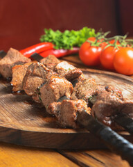 Marinated shashlik cooked on a barbecue grill over charcoal. Shashlik or Shish kebab served on a wooden board