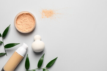 Makeup sponge with tonal foundation and powder on light background