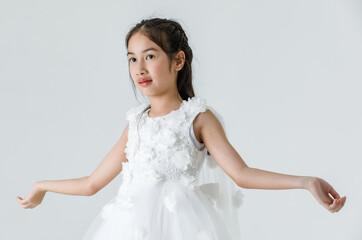 Isolated full body studio shot of little cute pretty Asian ballerina kid wears white beautiful roses flowers ballet dress and red shoes smiling posing dancing happily in front of white background