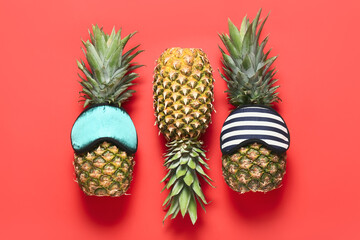 Fototapeta premium Fresh pineapples in sleeping masks on color background