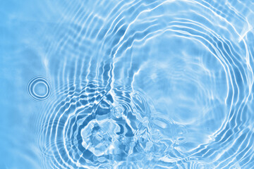 Blurred transparent blue colored clear water surface texture. Water waves in sunlight.