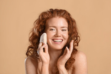 Beautiful young woman with makeup sponge on color background
