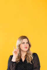 Creative idea. Advertising banner. Weight loss diet. Body positive. Inspired pensive overweight obese woman pointing up presenting something invisible isolated on orange copy space.
