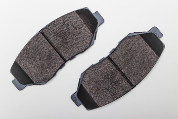 Two brake pads on a flat surface diagonally. Set of spare parts for car brake repair. Details on...