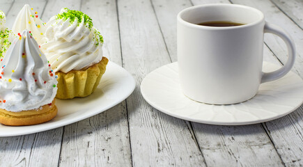 Cupcake with cream, white cup with tea on a light wooden background. The concept of breakfast, afternoon tea, sweet food. Top and side view. Selective focus.