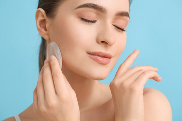 Beautiful young woman with makeup sponge on color background