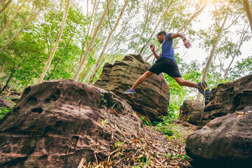 Sport running man in cross country trail run jumping on the rocky mountain path.