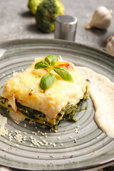Plate with tasty green lasagna on grunge background, closeup