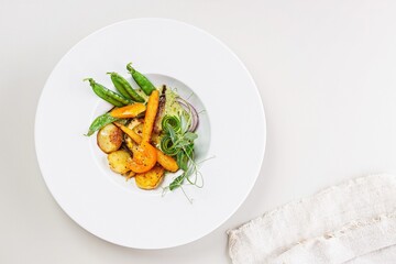 Vegetarian food. Baked zucchini, potatoes, tomatoes, sweet onions and green peas. Delicious and healthy organic vegetables. Restaurant recipe. Top view. Copy space