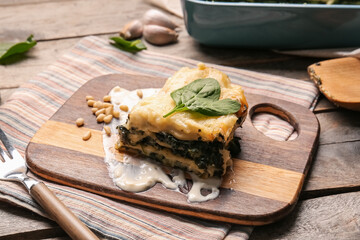 Board with tasty green lasagna on wooden background