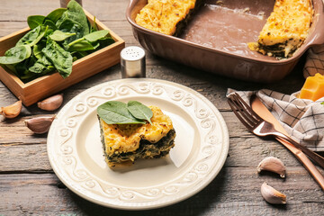 Plate with tasty green lasagna on wooden background