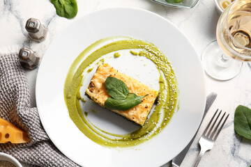 Plate with tasty green lasagna on light background