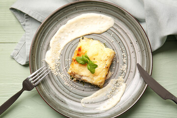Plate with tasty green lasagna on color wooden background