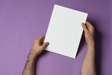 Hands holding a tri-fold brochure with blank pages on purple background, mock-up series template