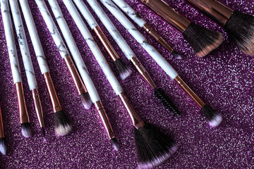 Makeup brushes on a a sparkly purple background