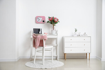 Comfortable workplace with laptop and protea flowers in interior of room