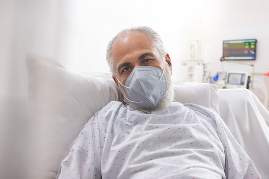 AN OLD MAN WEARING FACE MASK LOOKING AT CAMERA WHILE HOSPITALISED