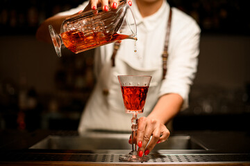 magnificent view of crystal glass with drink in which woman bartender pours liquid