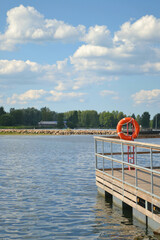 Pier on the lake with a flotation ring  in sunny summer day. Closeup. Vertical view.  
