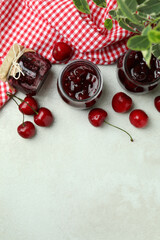 Cherry jam and ingredients on white textured table