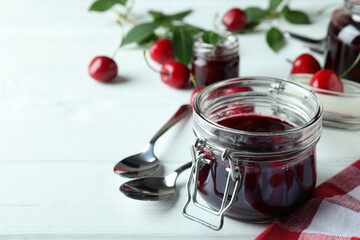 Cherry jam and ingredients on white wooden table