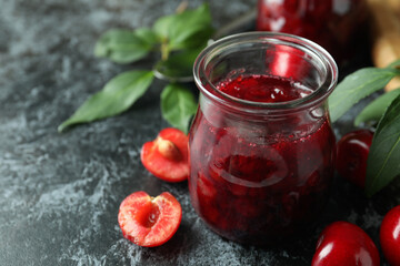Cherry jam and ingredients on black smokey table