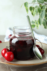 Cherry jam and ingredients on gray textured table