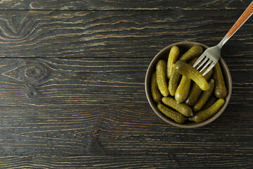 Fototapeta na wymiar Bowl of pickles and fork on wooden background