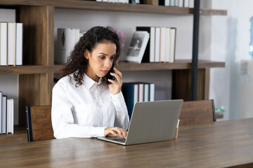 Happy excited successful Beautiful hispanic businesswoman working on laptop computer in modern office. Work from home and social distancing concept.