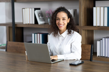 Happy excited successful Beautiful hispanic businesswoman working on laptop computer in modern...