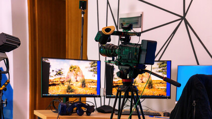Professional video camera on a stand with monitors on a table