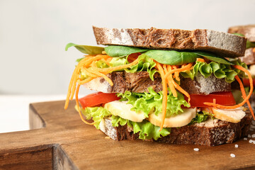 Board with tasty sandwich on light background, closeup