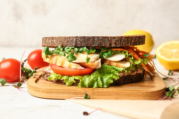 Board with tasty sandwich on light background, closeup