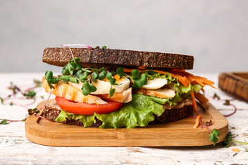 Board with tasty sandwich on light background, closeup
