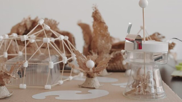 Tracking left of desk with various crafts from paper, cardboard, wooden sticks made by children