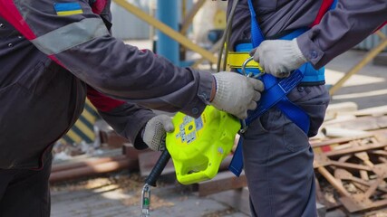 Industrial climber puts on equipment for high-altitude work. On climber s belt carabiners.