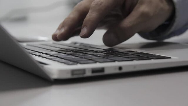 Hands are typing on a macbook keyboard. Close-up