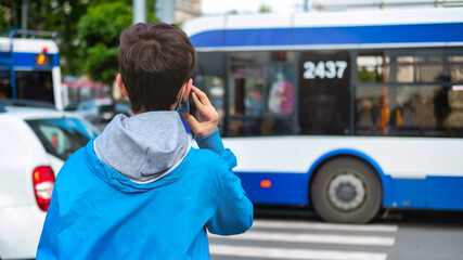 Young man talking on his phone near a road